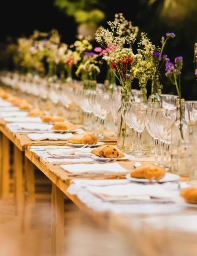 Tavola elegante con fiori, bicchieri e pane.